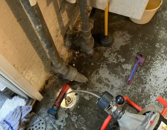 Commercial plumber doing a drain cleaning in the waste room shoreline plumbing